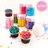 collection of sprink'd 6 cavity sprinkle jars in a range of colours stacked beside cupcakes with blue, yellow and pink icing