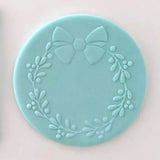 Christmas wreath pattern from debosser on round circle of blue icing