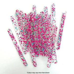 clear coloured with blue and pink glitter acrylic popsicle sticks spread out on white background