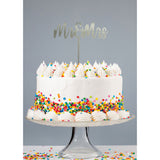 Silver Mr & Mrs acrylic cake topper atop white buttercream cake covered in rainbow confetti sprinkles atop a glass cake stand