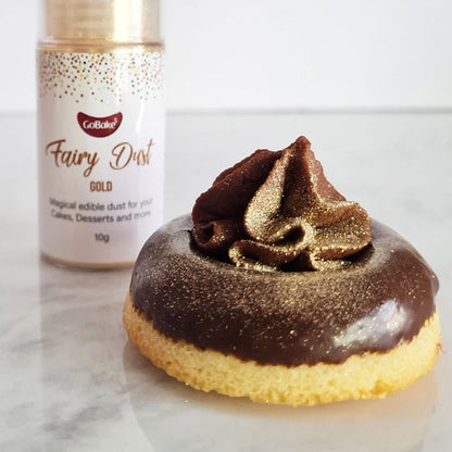 gobake gold edible fairy dust glitter sprayed on a treat with chocolate icing on a marble background