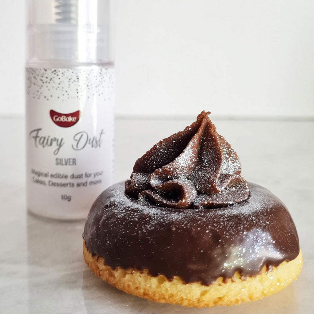 gobake silver edible fairy dust glitter sprayed on a treat with chocolate icing on a marble background